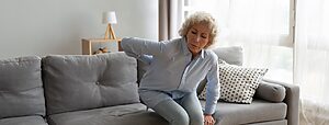 Senior woman standing up from couch