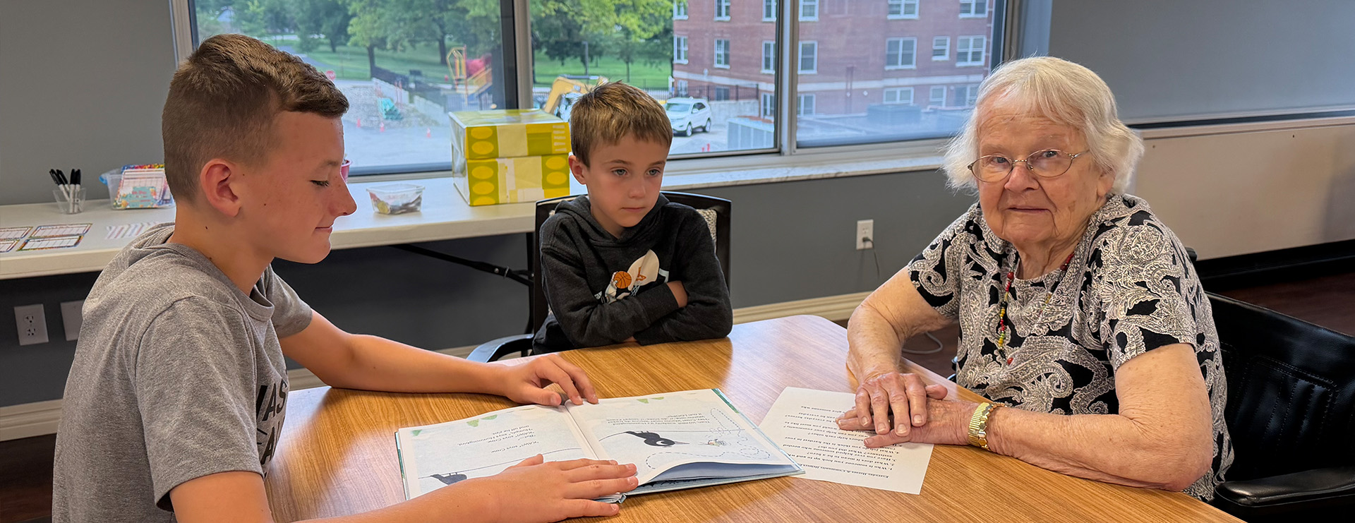 Senior woman and young boys reading after school